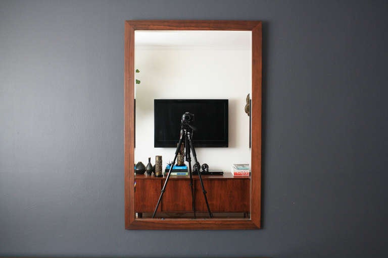 This is a vintage Mid-Century beveled mirror with a rosewood frame.