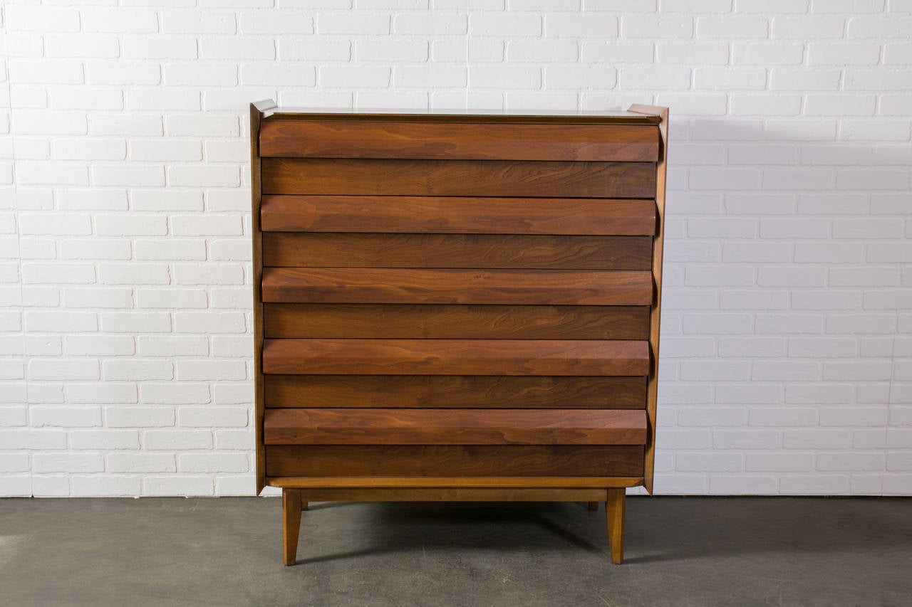 This is a Mid-Century Modern tall walnut dresser by Lane.  It has 5 drawers, the top one with one divider.