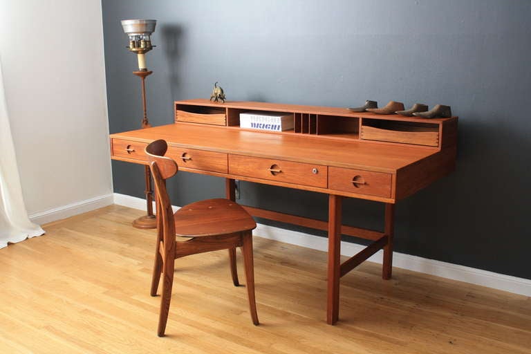 This vintage Mid-Century teak Lovig desk has a flip top to extend the desk top for more work space. It also has shelves behind the drawers. This desk is in great condition with minor age appropriate wear.