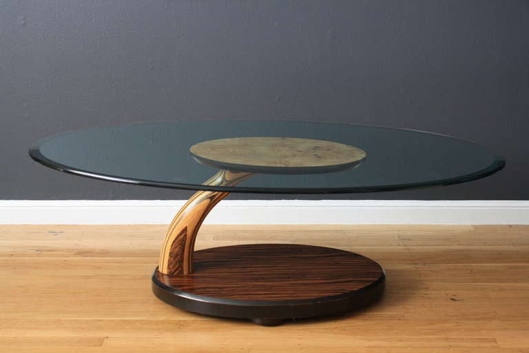 This vintage coffee table by Henredon has a glass top that rests on a exotic wood base. It is in great condition.