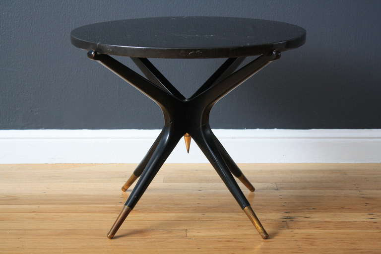 This is a Mid-Century Modern side table with a black base, black marble top and gold accents.