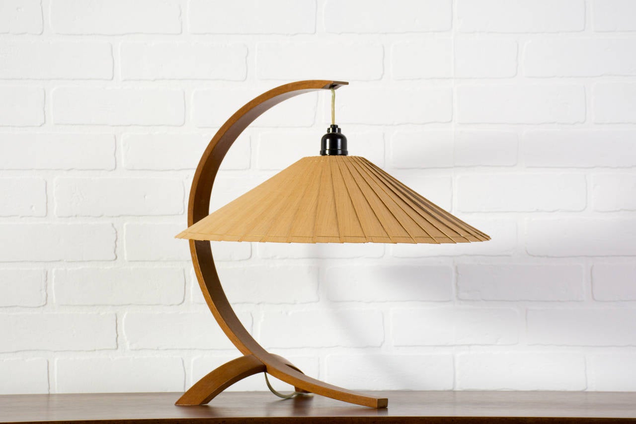 This is a Mid-Century Modern table lamp with a bent wood stand and a wood shade.

Measures 18