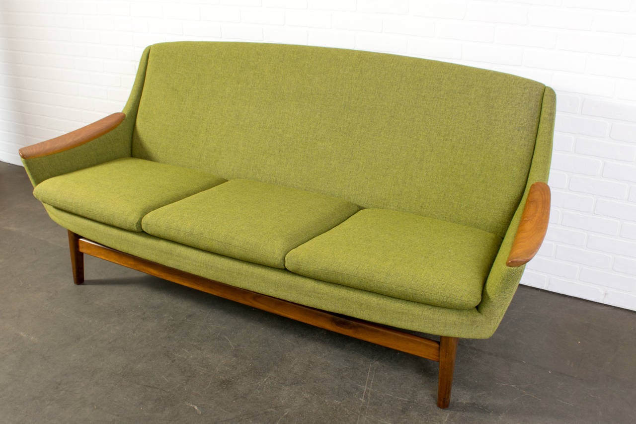 This is a Scandinavian Modern sofa with the original green upholstery and teak legs and armrests.