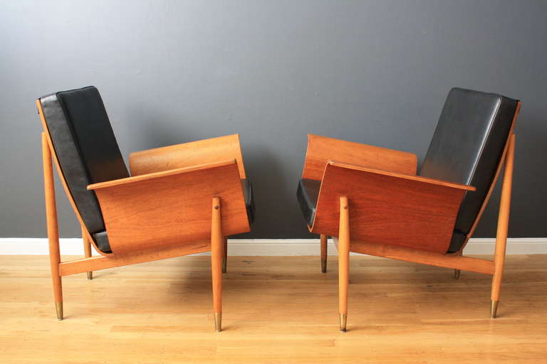 This is a pair of vintage Mid-Century bent wood lounge chairs with black leather cushions.