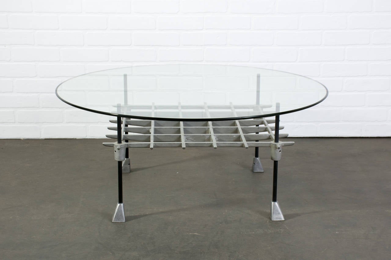 This is a Mid-Century Modern coffee table by Robert Josten. It has a cast aluminum base and a round glass top.