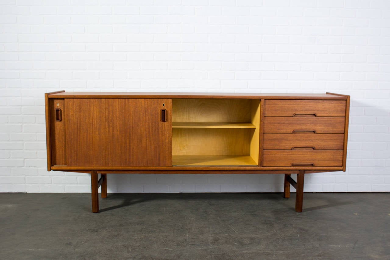 This is a vintage Mid-Century teak sideboard or credenza with two sliding doors and four drawers.
