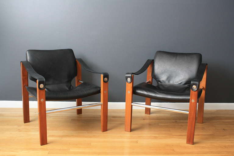 This is a pair of Mid-Century Modern safari lounge chairs that have been professionally reupholstered in black leather.