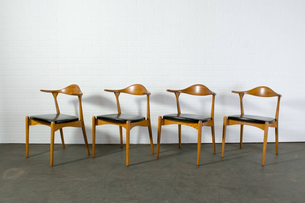 This is a set of four Mid-Century Modern dining chairs with sculptural wood frames and floating seats.