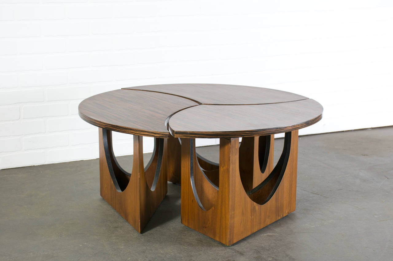 This is a Mid-Century Modern coffee table in three pieces. They can be used together to form a round table or separately. Macassar ebony top, walnut base.