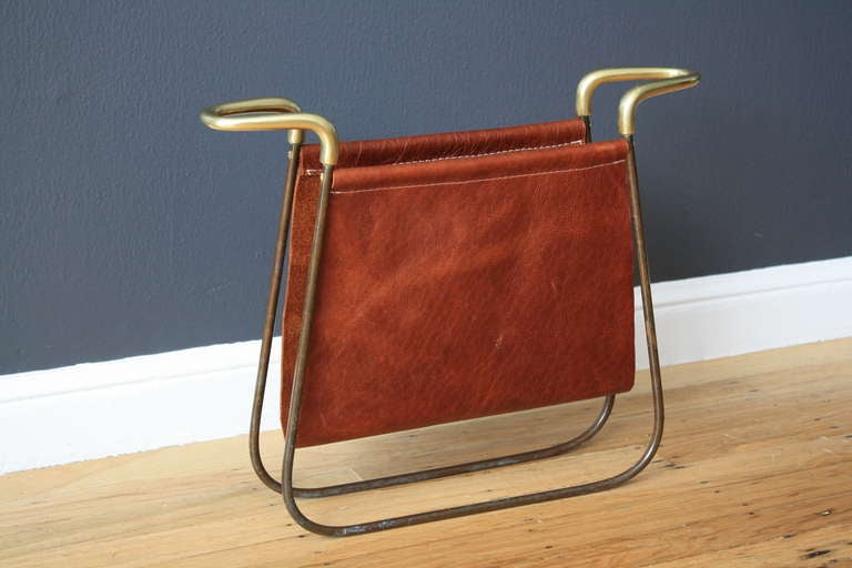 This is a vintage Mid-Century magazine rack by Austrian designer, Carl Aubock. It has a sculptural brass frame and new leather sling.