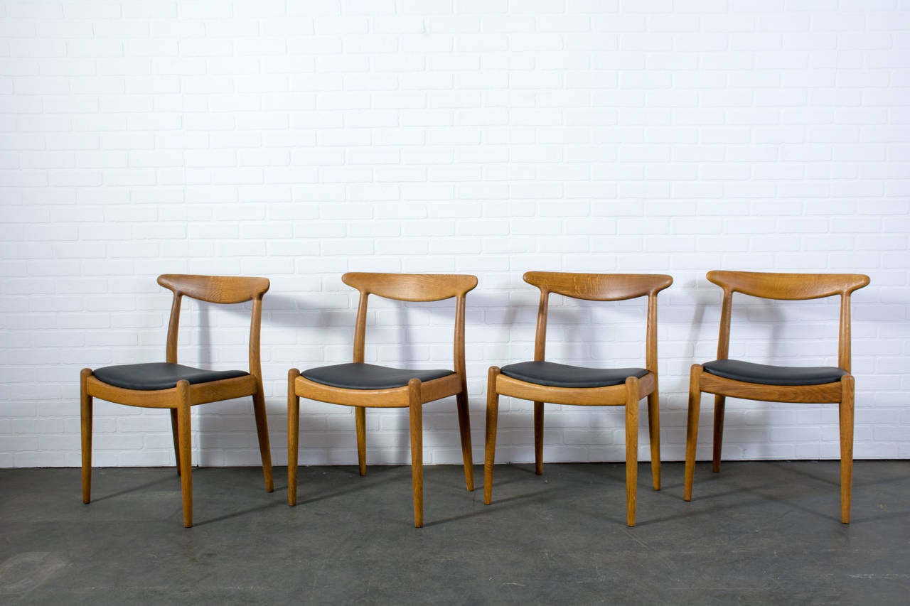 This is a set of four vintage midcentury chairs, model W2, designed by Hans Wegner in 1953 for CM Madsens. They are oak with black leather seats.