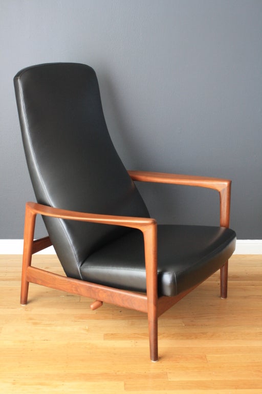 This Scandinavian Modern high back lounge chair was designed by Folke Ohlsson for Dux. It has a wood lever on the right side to recline, but can also be locked into an upright position. This chair has been professionally reupholstered in black vinyl.