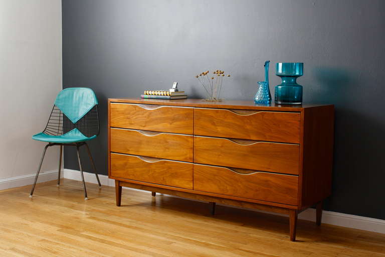 This is a Mid-Century Modern six drawers dresser by American of Martinsville.  It is walnut with gold metal accents on the drawers.