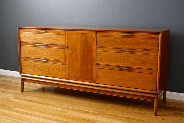 This is a vintage Mid-Century walnut dresser by Drexel. It has three drawers on each side, and three more concealed by a door, nine total.