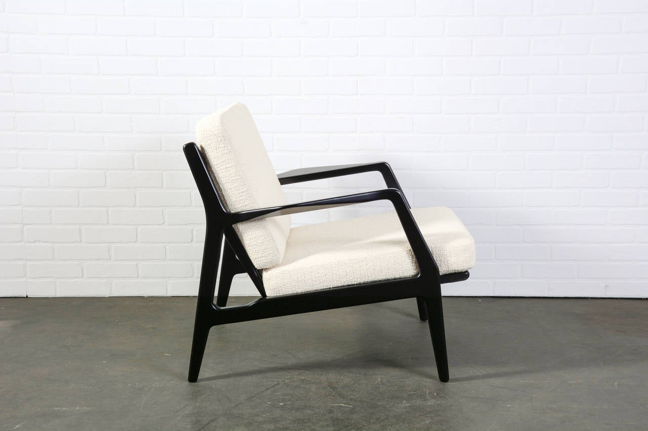 This is a vintage Mid-Century lounge chair by Ib Kofod Larsen. It has a black frame, professionally upholstered new cushions, and new Pirelli straps.