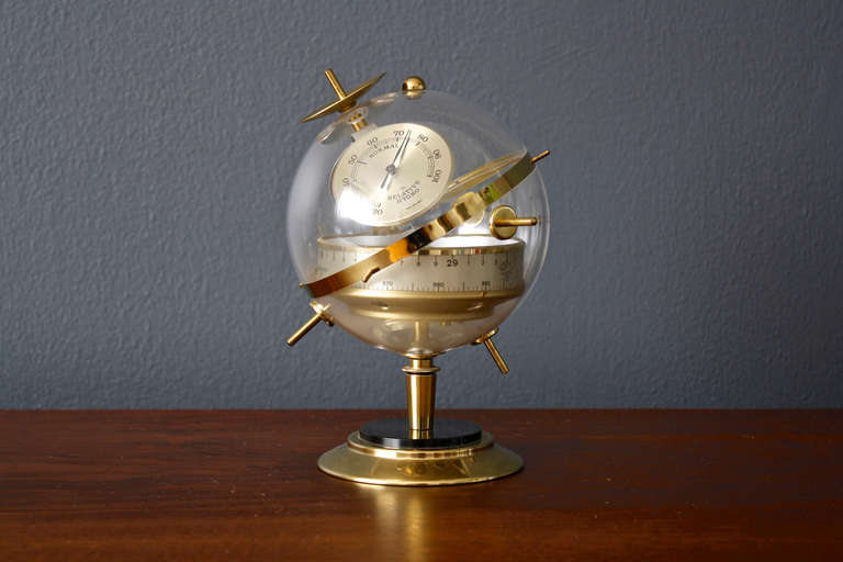 This is a vintage brass spherical Huger barometer, circa 1950.  It is a clear sphere on a round pedestal base and includes a temperature dial, relative humidity dial, and a horizontal band showing barometer pressure in inches of mercury and