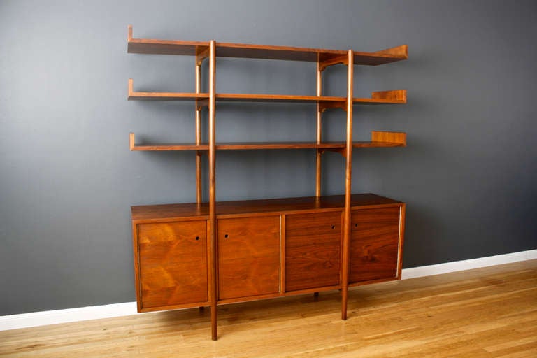 This is a an early and rare walnut credenza or room divider designed by Milo Baughman for Glenn of California. It has four doors below that conceal storage space with one adjustable shelf on each side.The credenza doors have small round finger holes