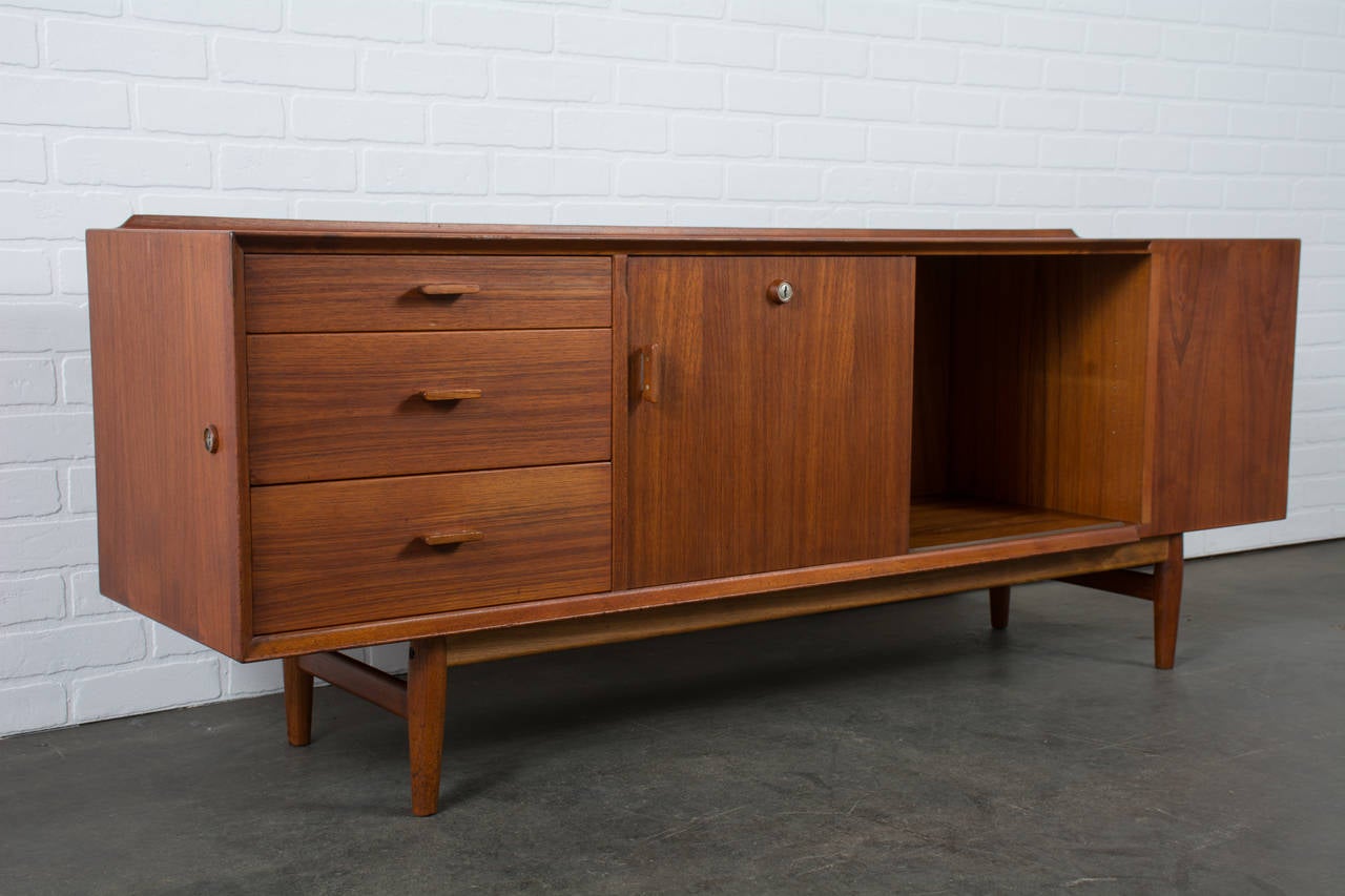 This vintage Mid-Century teak sideboard was designed by Arne Vodder for Sibast in the 1960s, Denmark (Model 211). It features three drawers on the left, five colorful drawers in the middle (original colors), a sliding door that conceals another