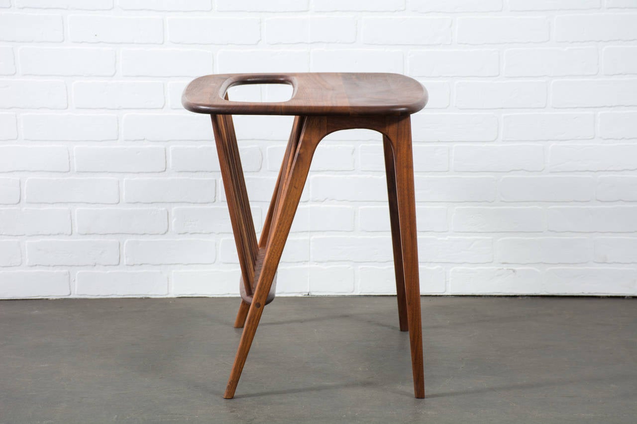 This Mid-Century Modern walnut side table was designed by Arthur Umanoff and manufactured by Washington Woodcraft in the 1960's. It features a built in magazine rack.