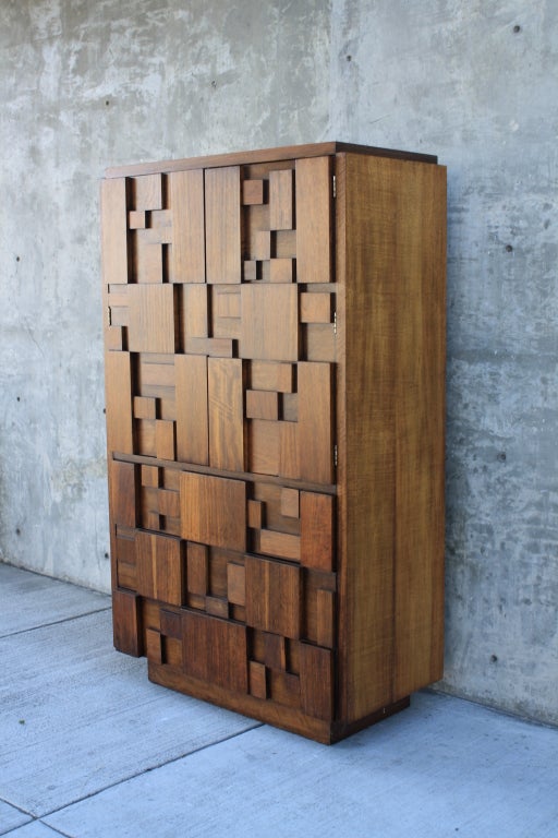 This is a Mid-Century Modern brutalist walnut dresser/chest by Lane. This tall storage piece has three drawers below and two doors above that conceal one drawer and two adjustable shelves.