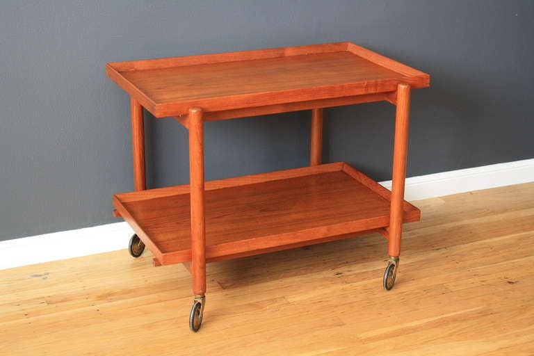 This is a vintage Mid-Century tea/bar cart by Poul Hundevad.  It rolls on casters and the top tray slides over, so that the bottom tray can be removed and used next to it for more space above (making it 59