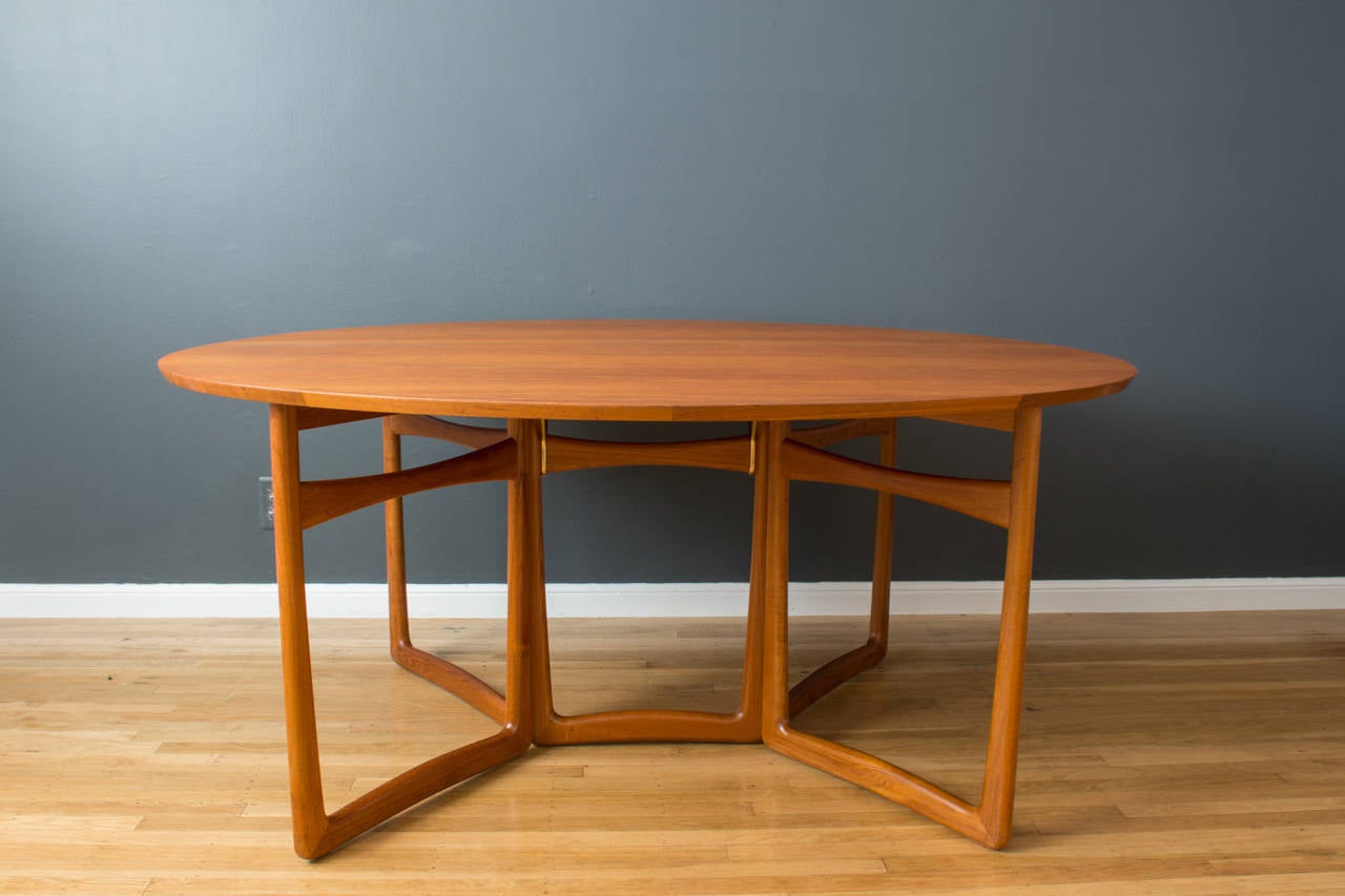 This is a vintage Mid-Century solid teak dining table designed  by Peter Hvidt and Orla Molgaard Nielsen for France & Son in the 1950's, Denmark. It has elegant sculptural legs that fold together, so that the oval top can be folded down for easy