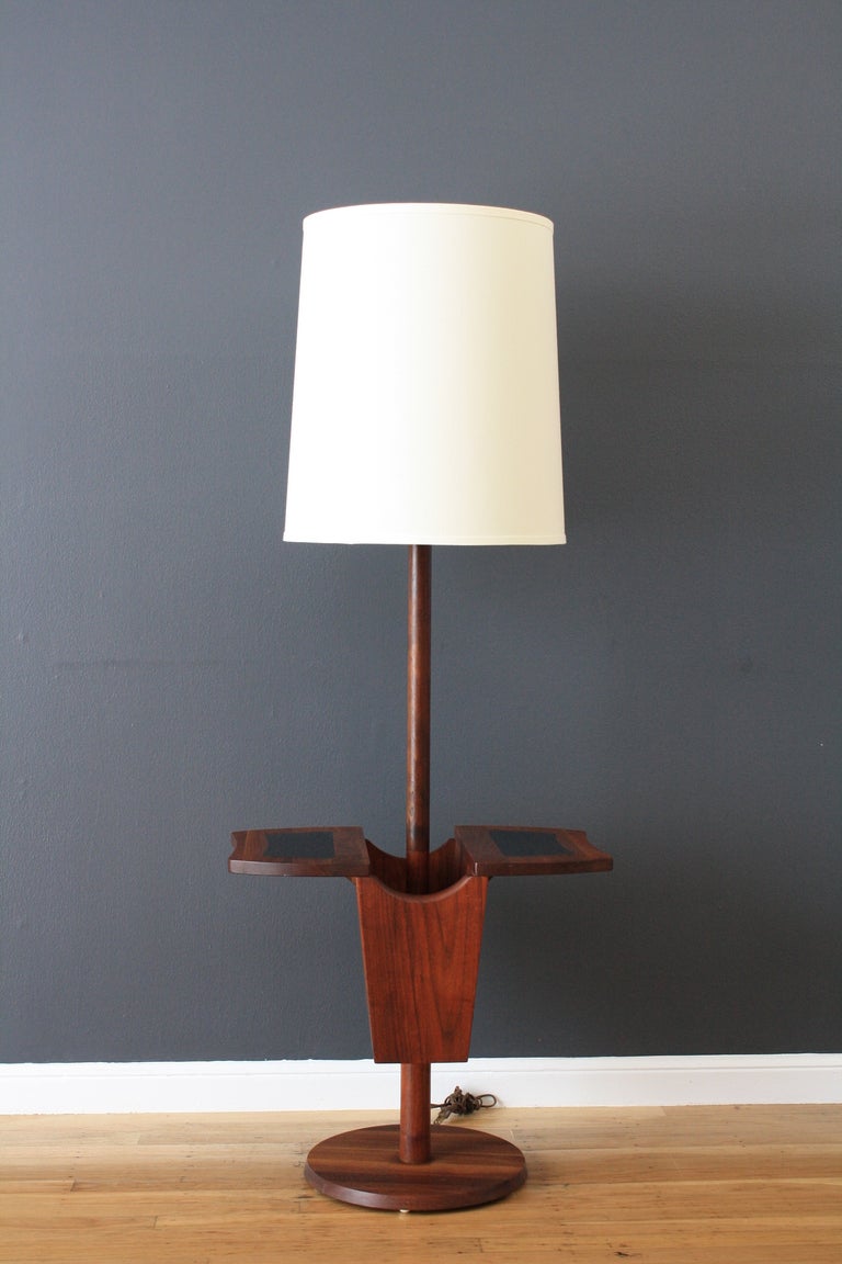 This vintage Mid-Century solid walnut floor lamp is versatile with a built-in magazine rack or space to store books, etc.  It also has a small table top with a black in-lay on both sides.  The new 16