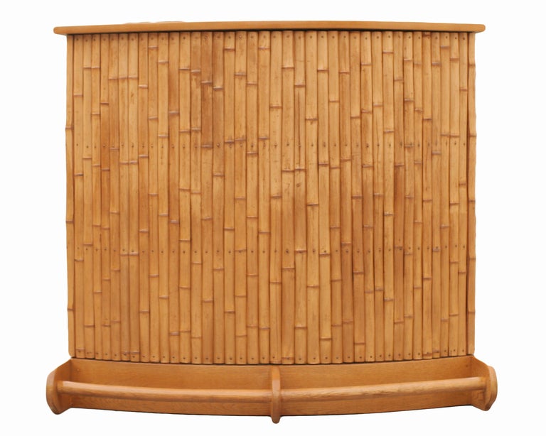This 1939 standing bar is finished on three sides with bamboo poles which are held in place with rust-proof handmade copper nails; the cabinet, including the base and top, is rendered in solid mahogany; the drawer pulls are rattan. The back features