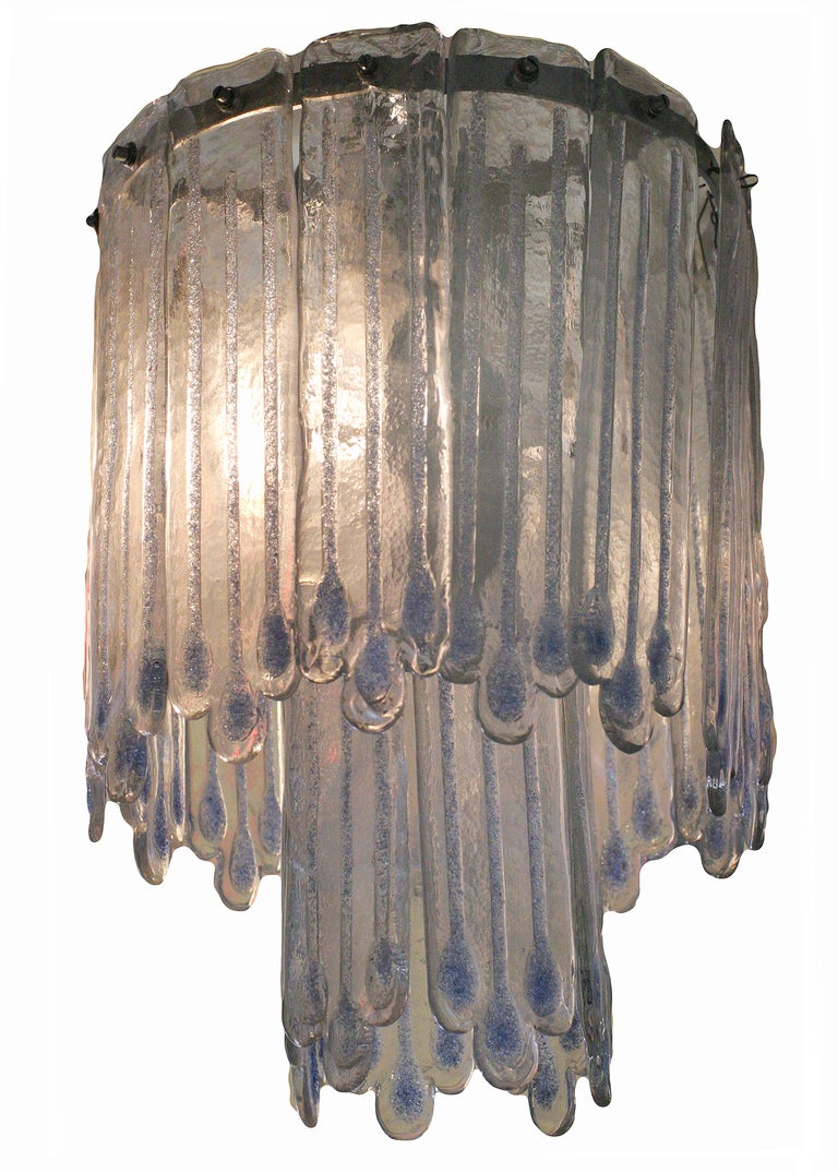 This Mid-Century Modern chandelier attributed to Mazzega features two-tiers of icicle-like opaline Murano glass. Inside the shorter tier there are three bulbs with a fourth in the center of the longer tier.