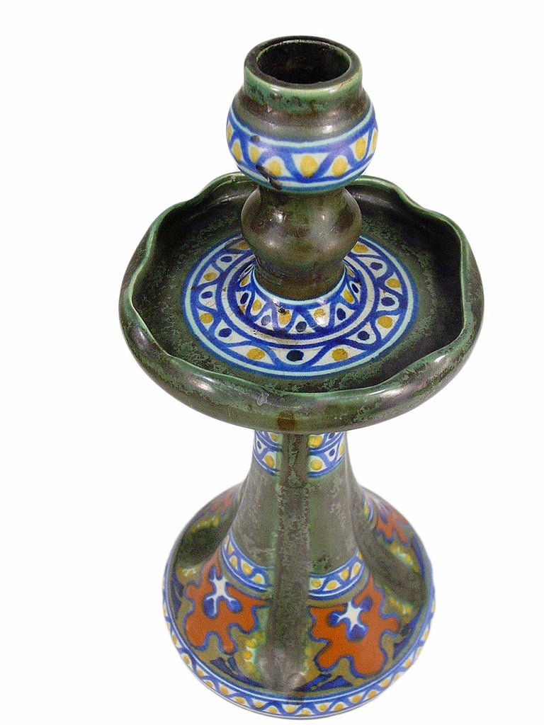 This Gouda candlestick was made at the Plateelbakkerij Zuid-Holland (PZH) factory between 1906 - 1917. The semi-matte piece is hand-painted in the 
