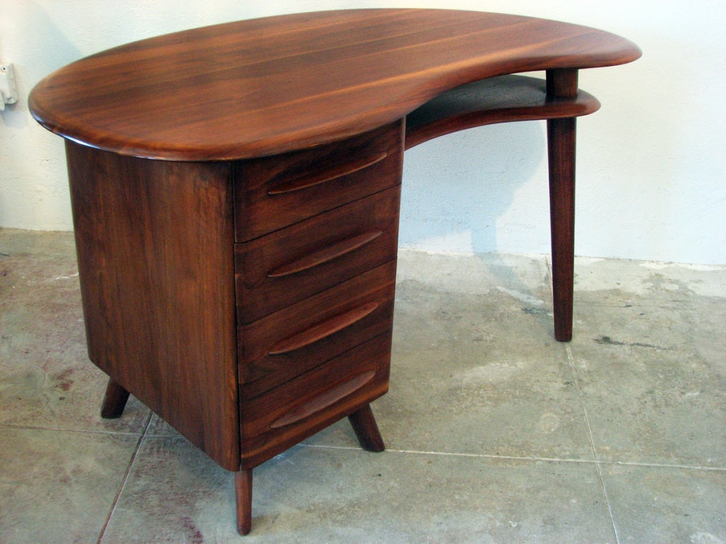 This mid-century modern writing desk by Carl Bissman features a free-form surface with three drawers and solid walnut construction.
Bissman Furniture of Springfield, Missouri only manufactured pieces from the 1940s-1950s but retains a devoted