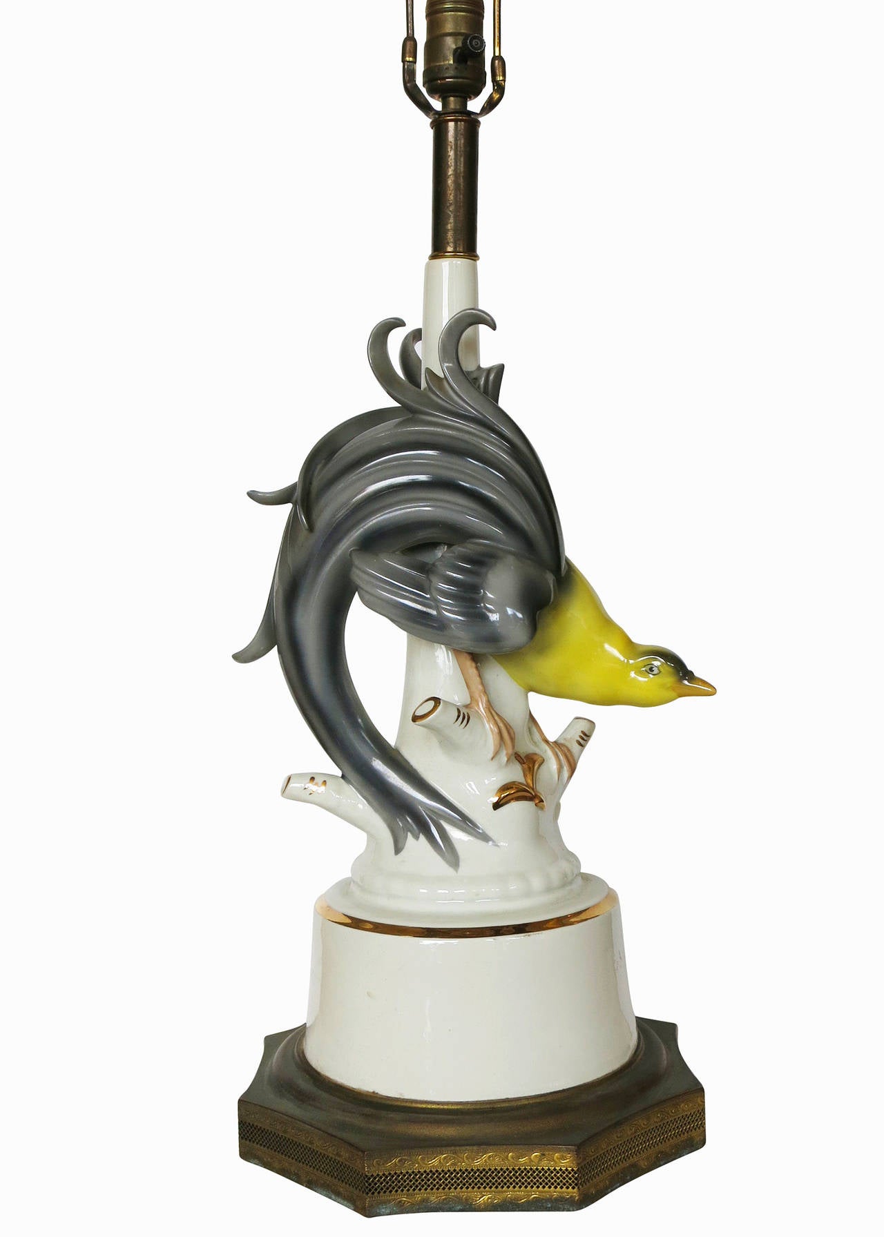 Made circa 1950, this ceramic lamp pair was modeled after blue and yellow greater Bird of Paradise. The birds are perched atop white, ceramic tree branches with gold detail that rest on decorative gilded brass bases.