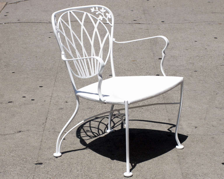 Woodard outdoor white painted iron armchairs with decorative Art Nouveau inspired scrolling floral motif along the back and original molded wicker-style seat. All pieces professionally restored. 

An assortment of vintage patio tables that from seat