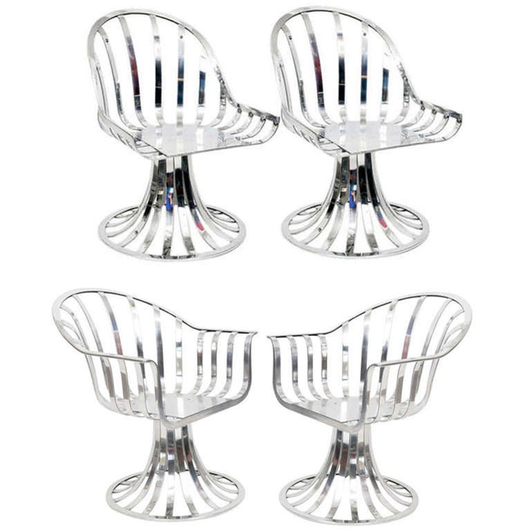 Set of four slatted aluminum with matching table featured in this set are two arm chairs and two side chairs designed by Russell Woodard circa 1960. 

Mirror polished and lacquer sealed these chairs can be used indoors or out. Ready to be