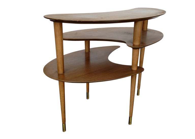 Designed by John Keal and manufactured by the Los Angeles based Brown-Saltman Company, this vintage side table was one of several boomerang-inspired tables. It features three biomorphic tiers sitting on four tapered legs, caped with brass feat.