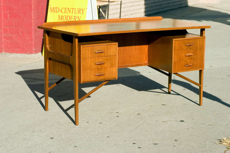 Large Danish teak desk in the style of Kai Kristiansen with floating drawers and table top. The desk features six side drawers, a curved front lip and a 50