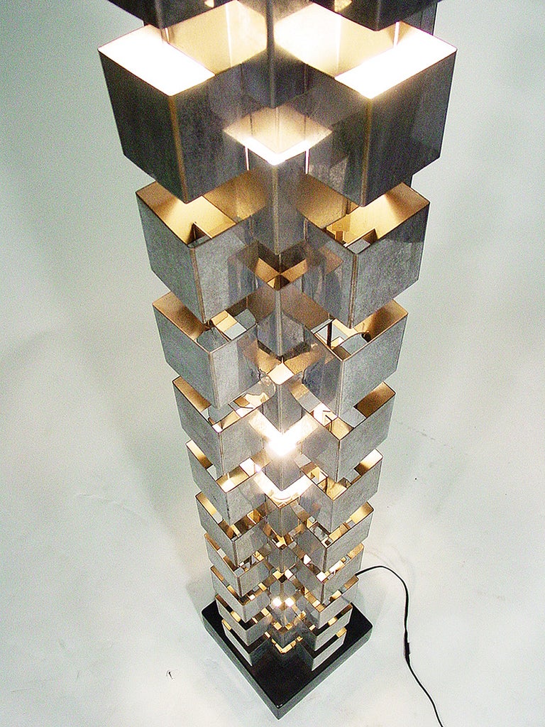 This architectonic Curtis Jere skyscraper floor lamp rendered in hand-forged, interlaced chrome brackets casts light upwards and through the openings. Lamp takes two bulbs and is mounted on a black metal stand.