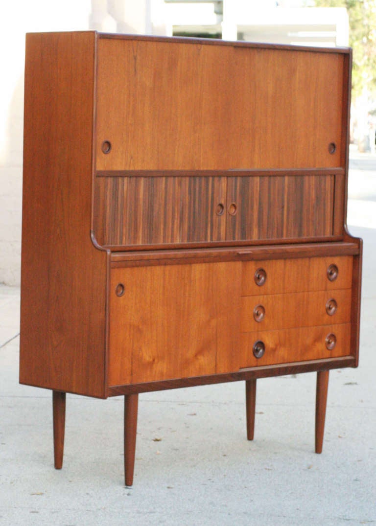 Modernist Teak Credenza with built in Hutch and pull out Bar shelf, Denmark. High quality cabinet with subtle modernist teak front, containing three off central drawers, three felt lined trays and 4 open cubby spaces each with an adjustable shelf.