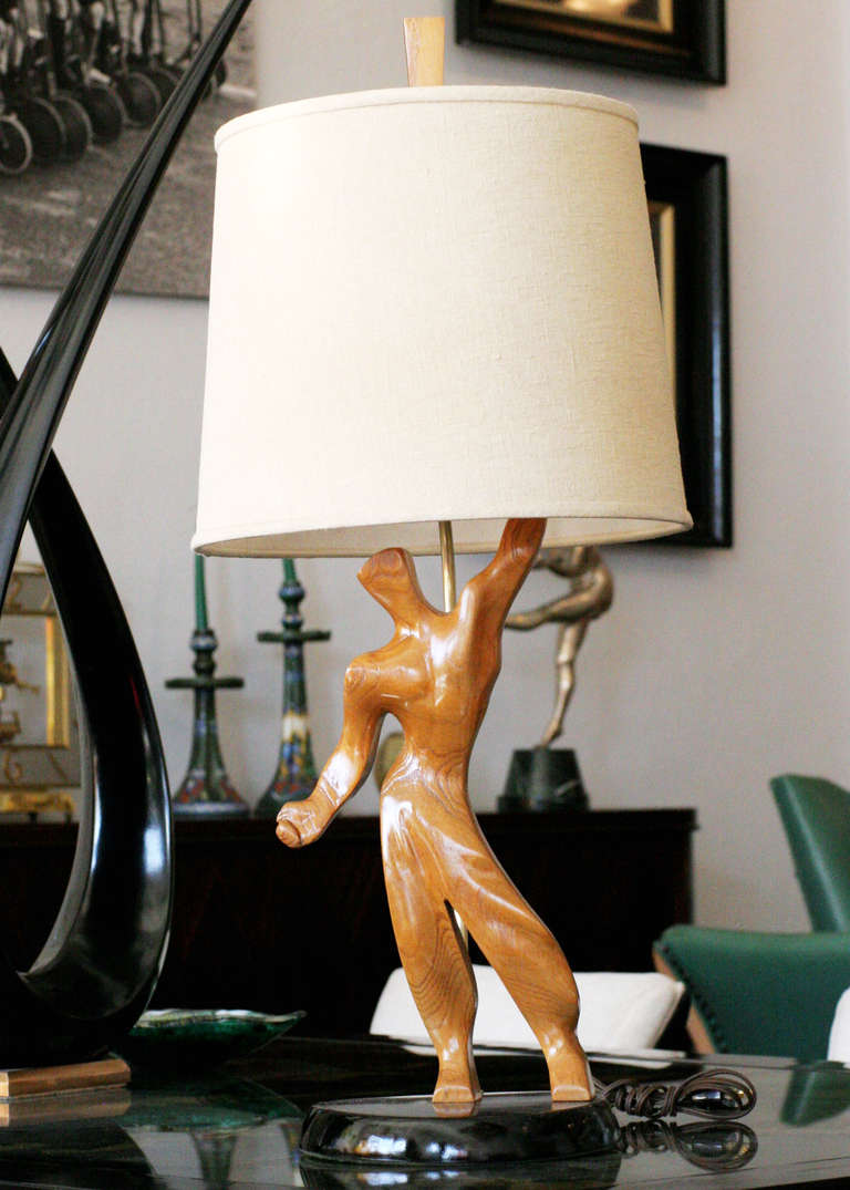 Mid-Century era hand-carved table with abstract male figure fixed to a black lacquer base. 

The lamp is reminiscent of the styling made popular in the era by Heifetz but yet still keeps a unique form all its own,

circa 1950.