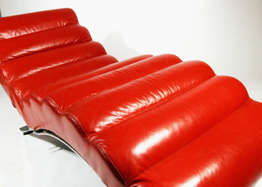 This Eileen Gray Bibendum style red leatherette chaise lounge with an undulating chrome base features an adjustable back that reclines by pulling up the side lever. The piece is in excellent condition with original hardware and finish. Running size