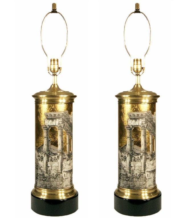 These Mid-Century Modern Piero Fornasetti columnar table lamps feature lithographically printed 19th century images of Roman ruins set off against a gold foil background. Each lamp bears the Italian inscription “Avanzo del Tempio della Concordia,”