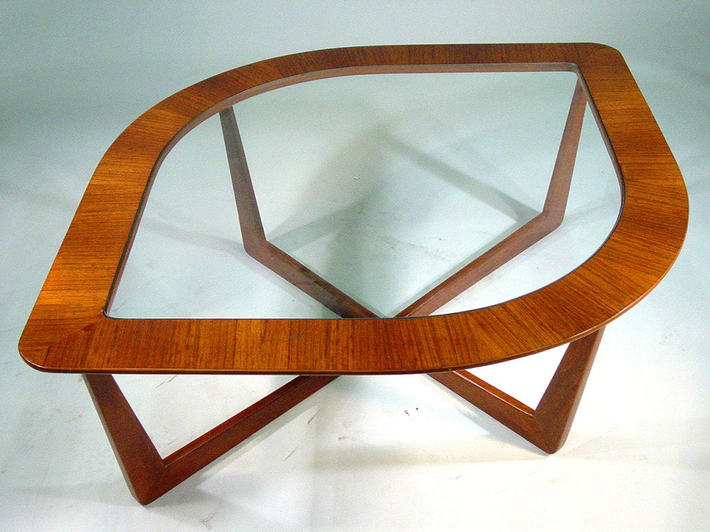 This sculptural mid-century modern coffee table by Lane features an unusual eye-shaped frame in a highly figured wood frame inset with a glass top. The table rests on an x-shaped base.
