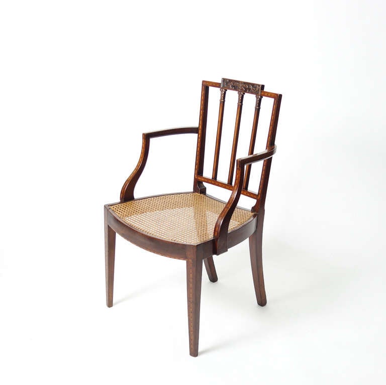 A graceful chair with a wonderful sense of balance, of carved and inlaid mahogany, with pierced, arcaded back and down-curved arms above a bowed seat. Square, tapering legs. The inlay is quite refined, the proportions intuitively satisfying. Stamped