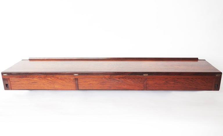A pristine example of this Danish mid-century classic. The streamlined desk, with its near absence of ornament, seems to float, yet the densely figured grain of the rosewood gives it substance and warmth. A beautifully made thing, its details--from
