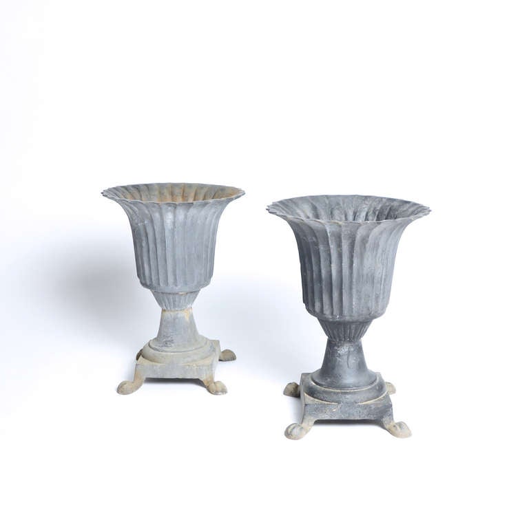 These urns have a neoclassical simplicity, and wear their age well, from their fluted tops to their paw feet.