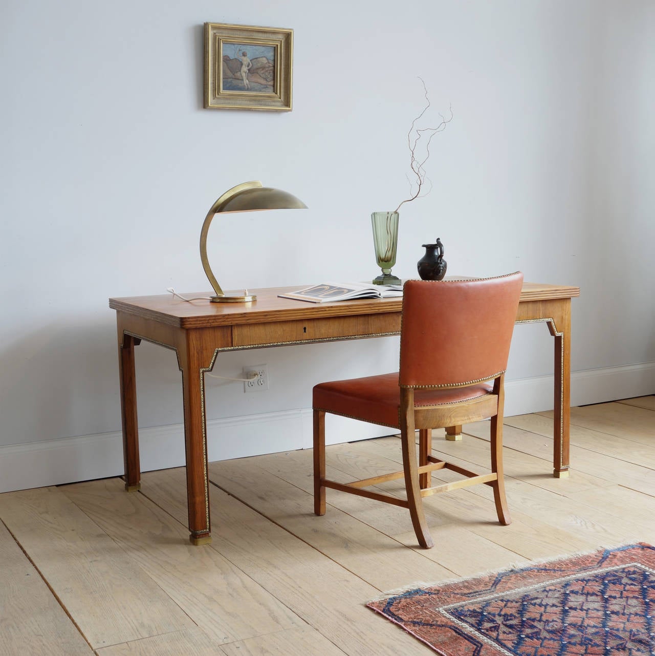 From the bookmatched rosewood veneer of the top to the gilt-tooled leather border and down to the square brass sabots, this desk is an object of impeccable beauty. The thoughtful ornamentation elevates the piece from utilitarian to luxurious. Notice