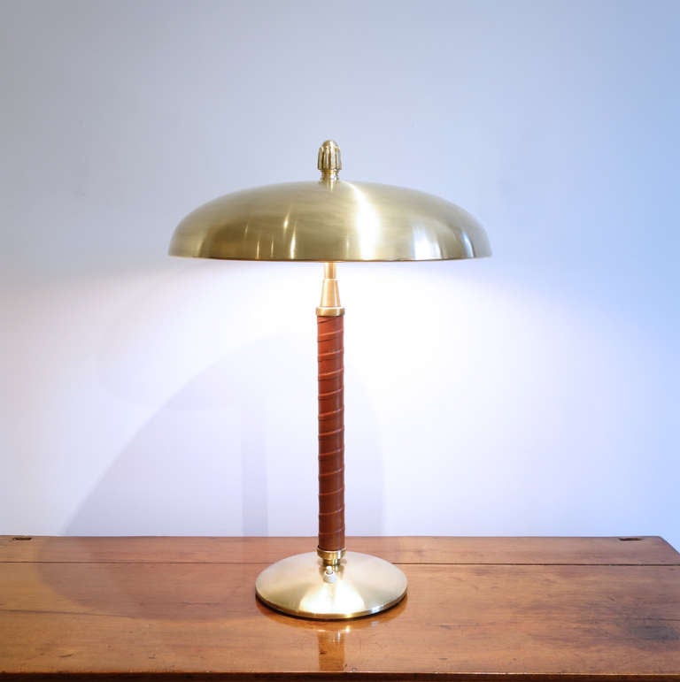 A handsome, Swedish modern table lamp with brass shade and base and leather-wrapped stem.