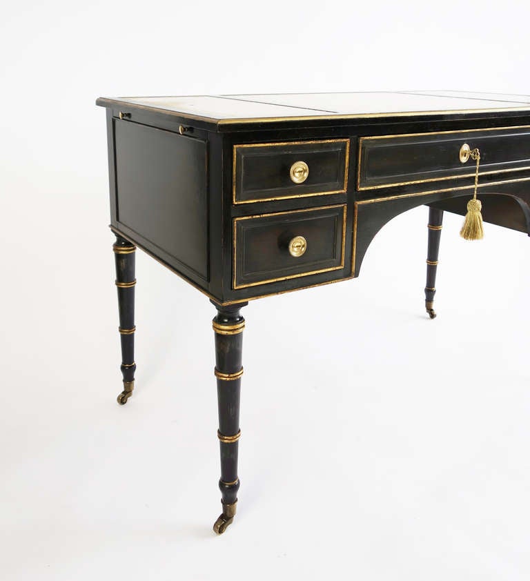 A handsome French writing desk with five drawers and two pull-out extensions. Gilt and ebonized wood, with faux bamboo legs and brass hardware. The top wears its original embossed leather. 