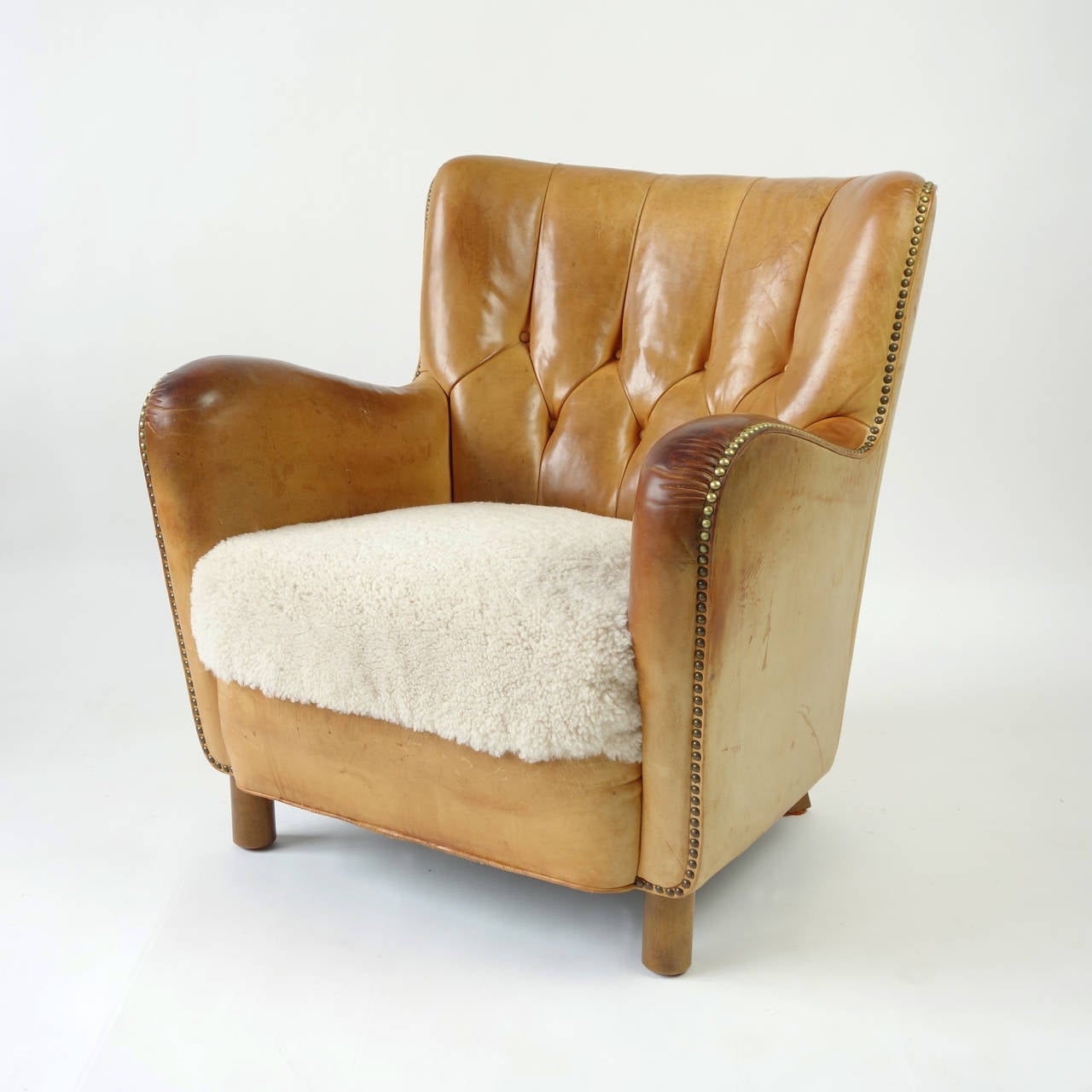 The original leather has achieved a gorgeous pale cognac color, and remains supple under the hand. The seat is upholstered in a dense shearling.