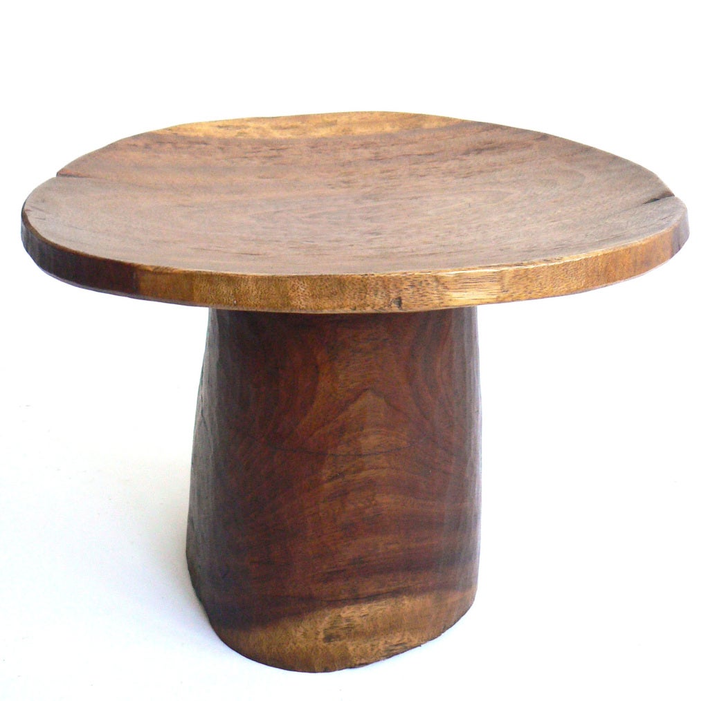Hand carved of a single block of exotic wood. We find that this unusual single-footed base makes for a simple, beautiful, and sturdy side table.